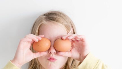 girl holding two eggs while putting it on her eyes