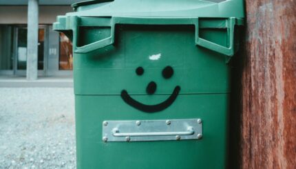 green trash bin on sidewalk